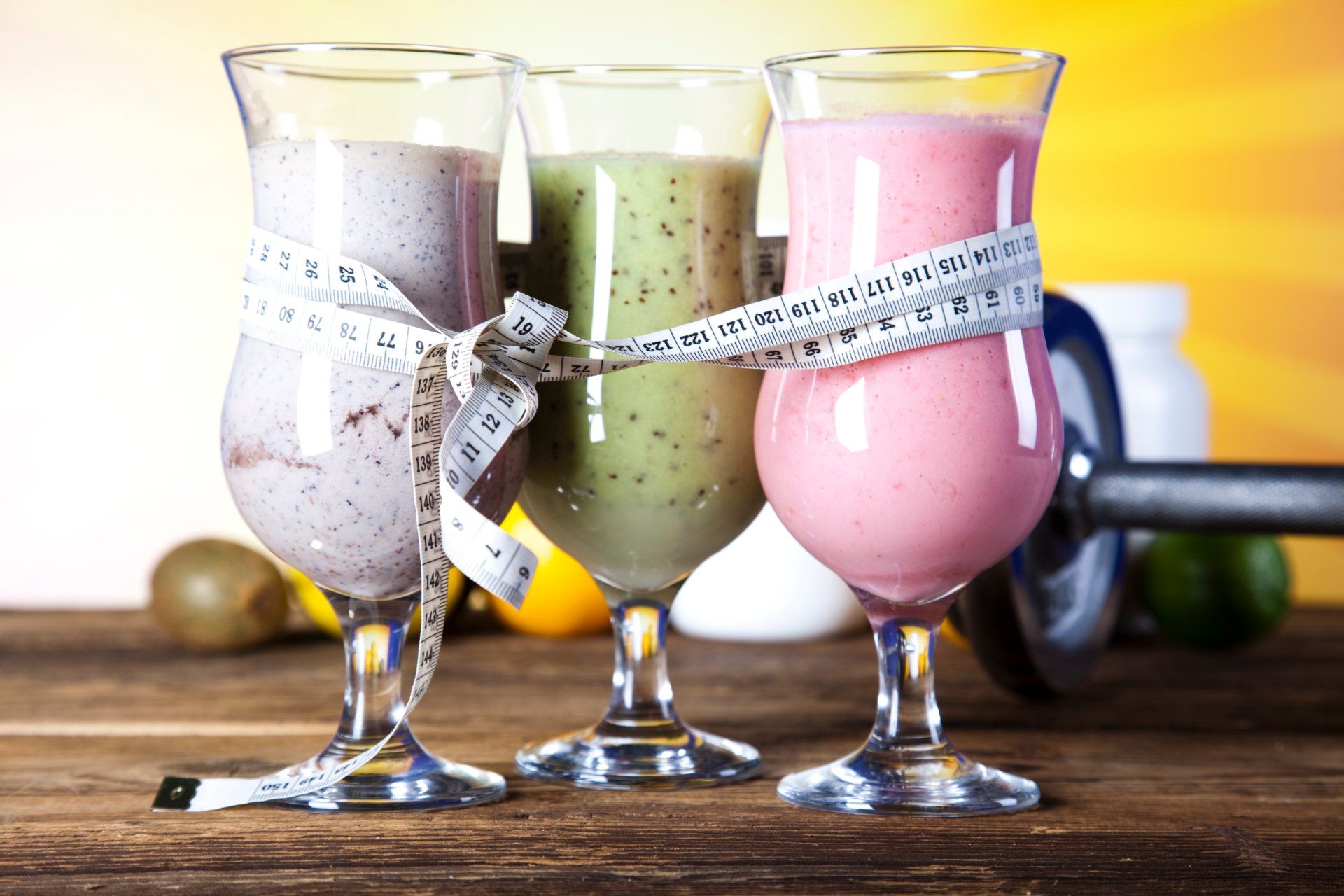 Three varieties of smoothies in glasses, tied together with a measuring tape