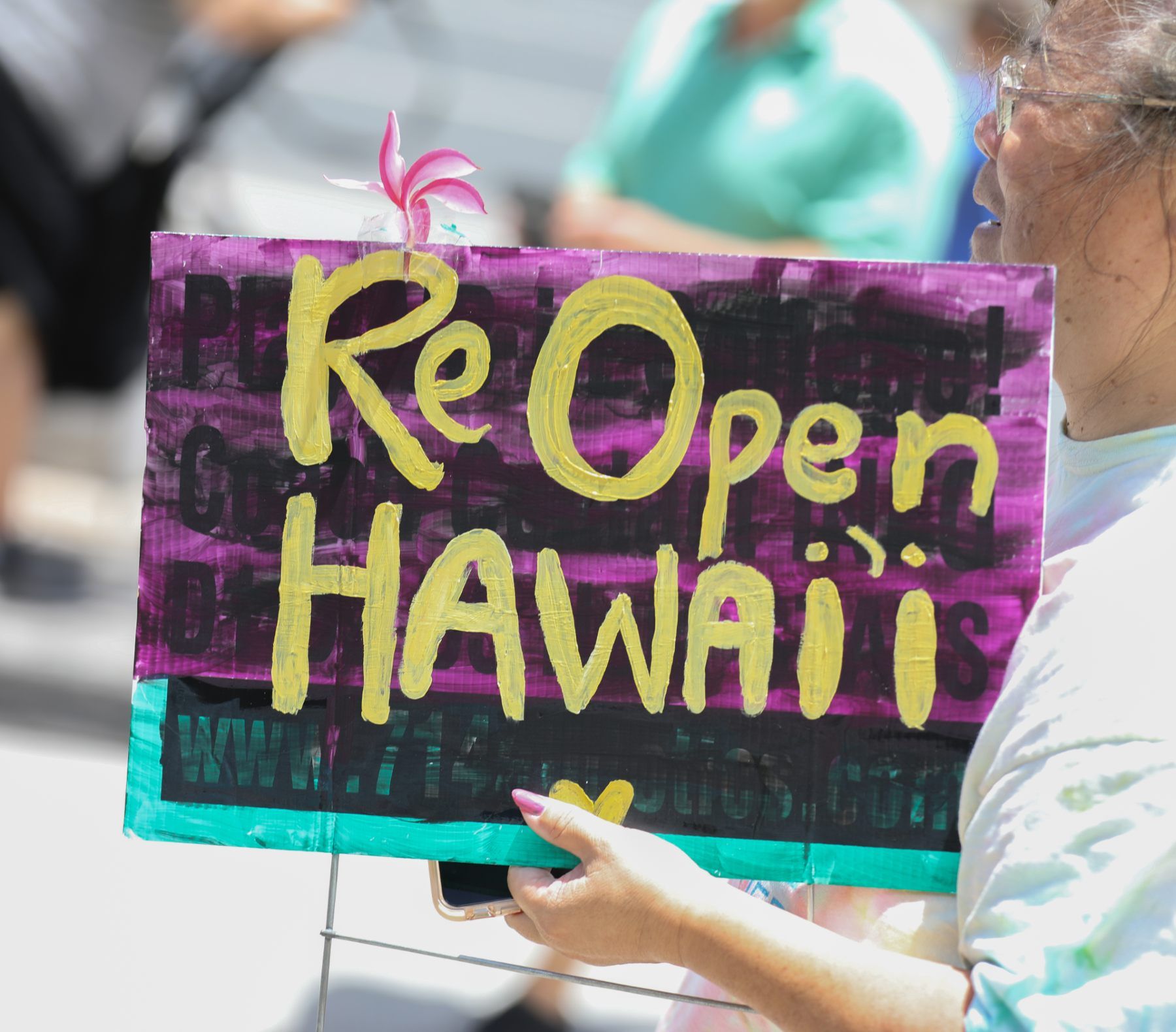 Woman holds sign that reads "Re Open Hawai'i"