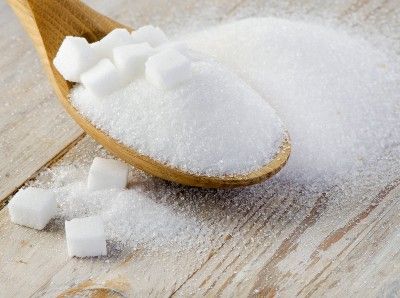Sugar on table and in wooden spoon