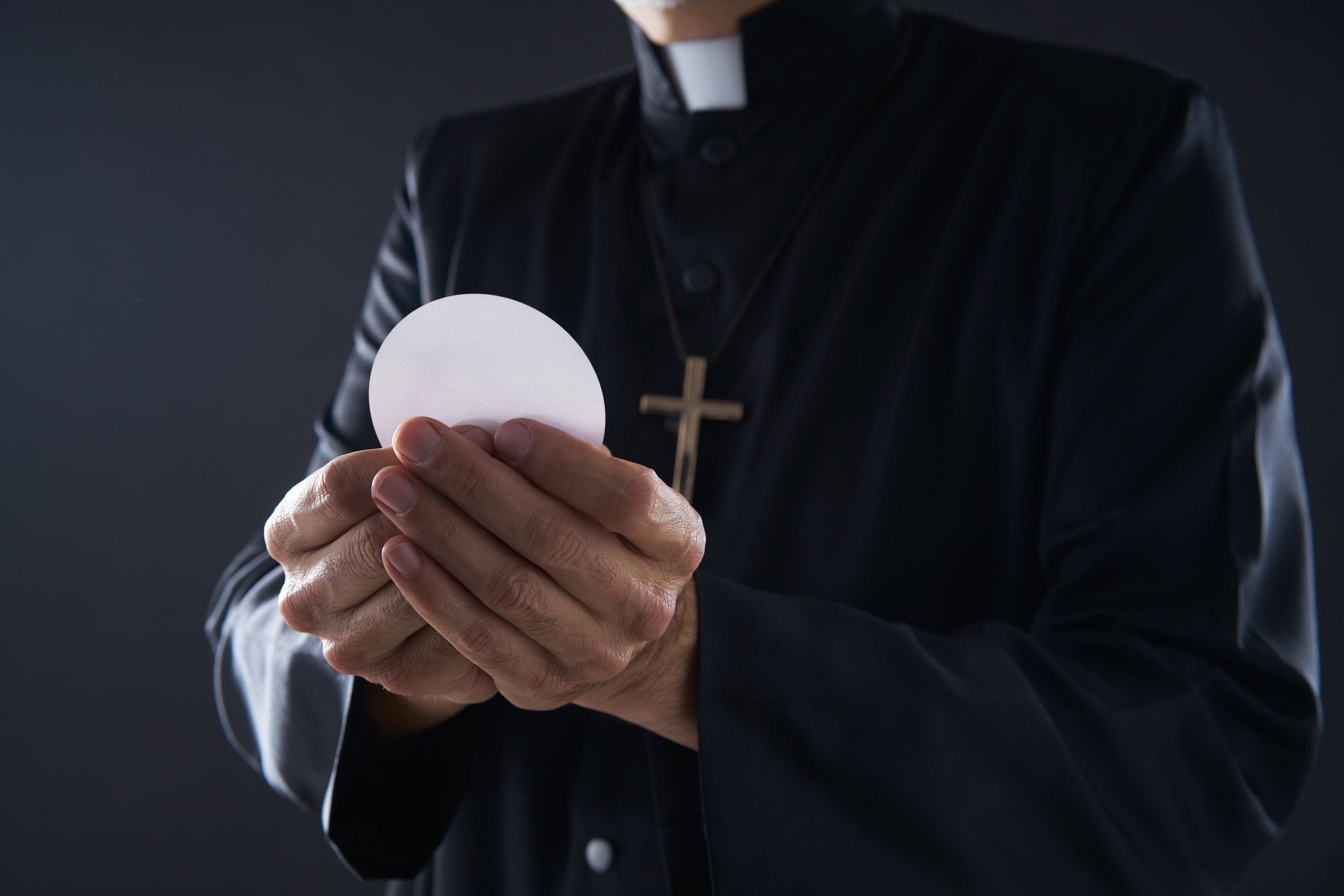 priest hands holding communion wafer