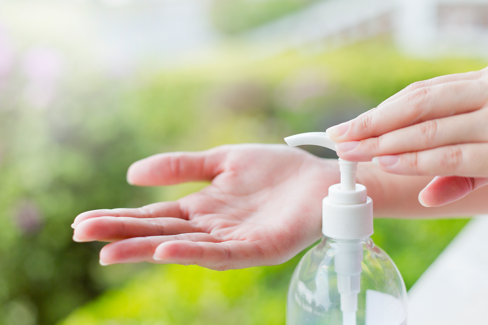 Person squeezing sanitizer into their palm from a bottle with a white pump