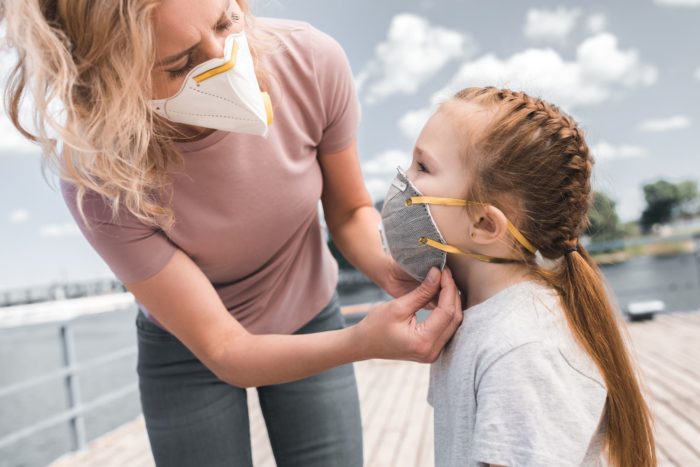 mom placing N95 protective face mask on child