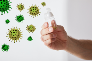 Illustration of germs and photo of hand holding open sanitizer bottle 