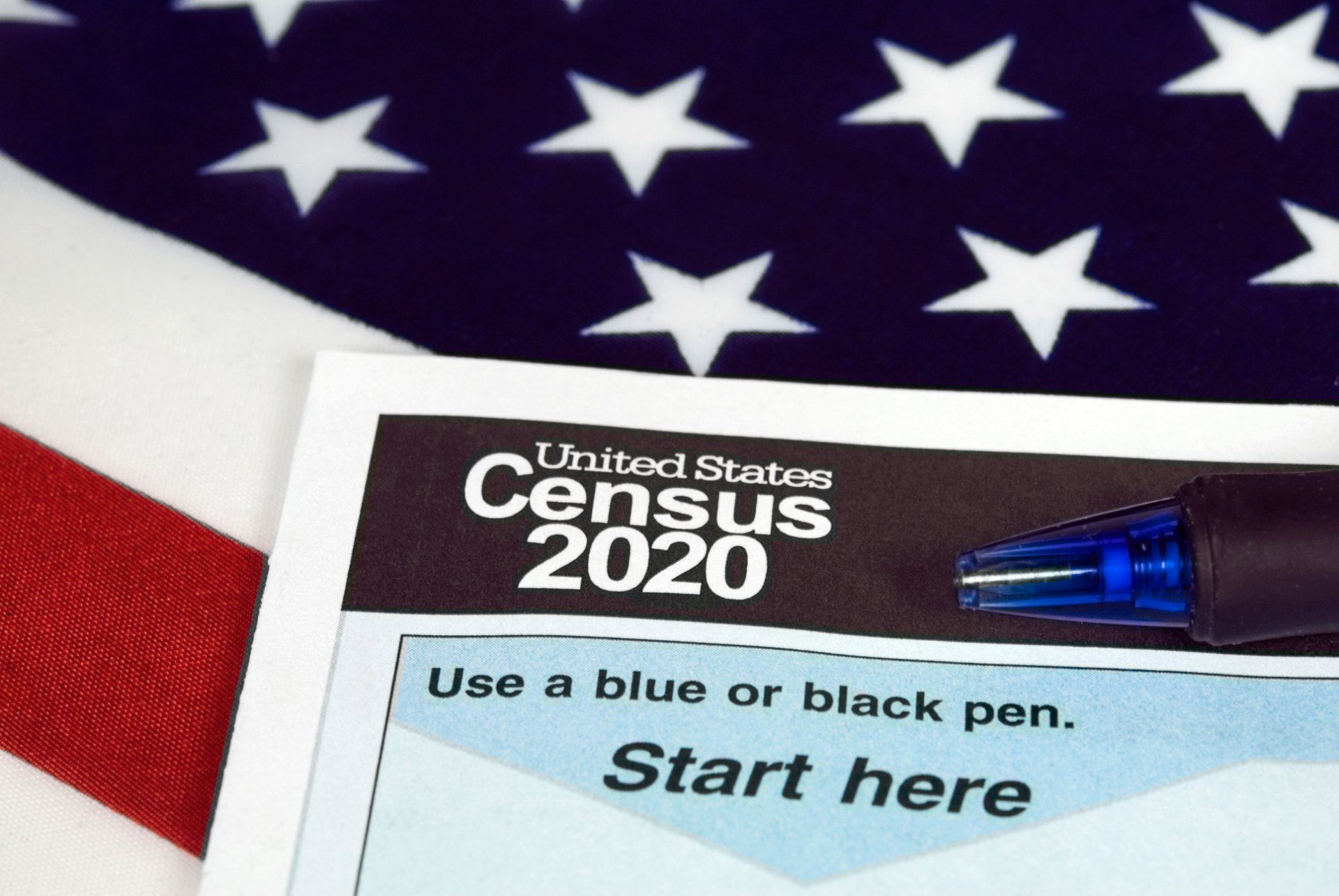 2020 Census form with blue pen, lying on top of U.S. flag - Census data