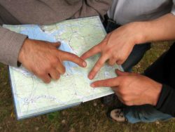 Closeup of three hands pointing at a map