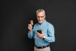 Older man checks debit card balance on cell phone