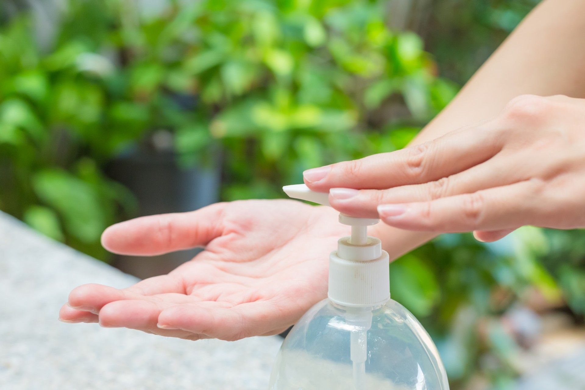 Woman outdoors pumping hand sanitizer into right hand