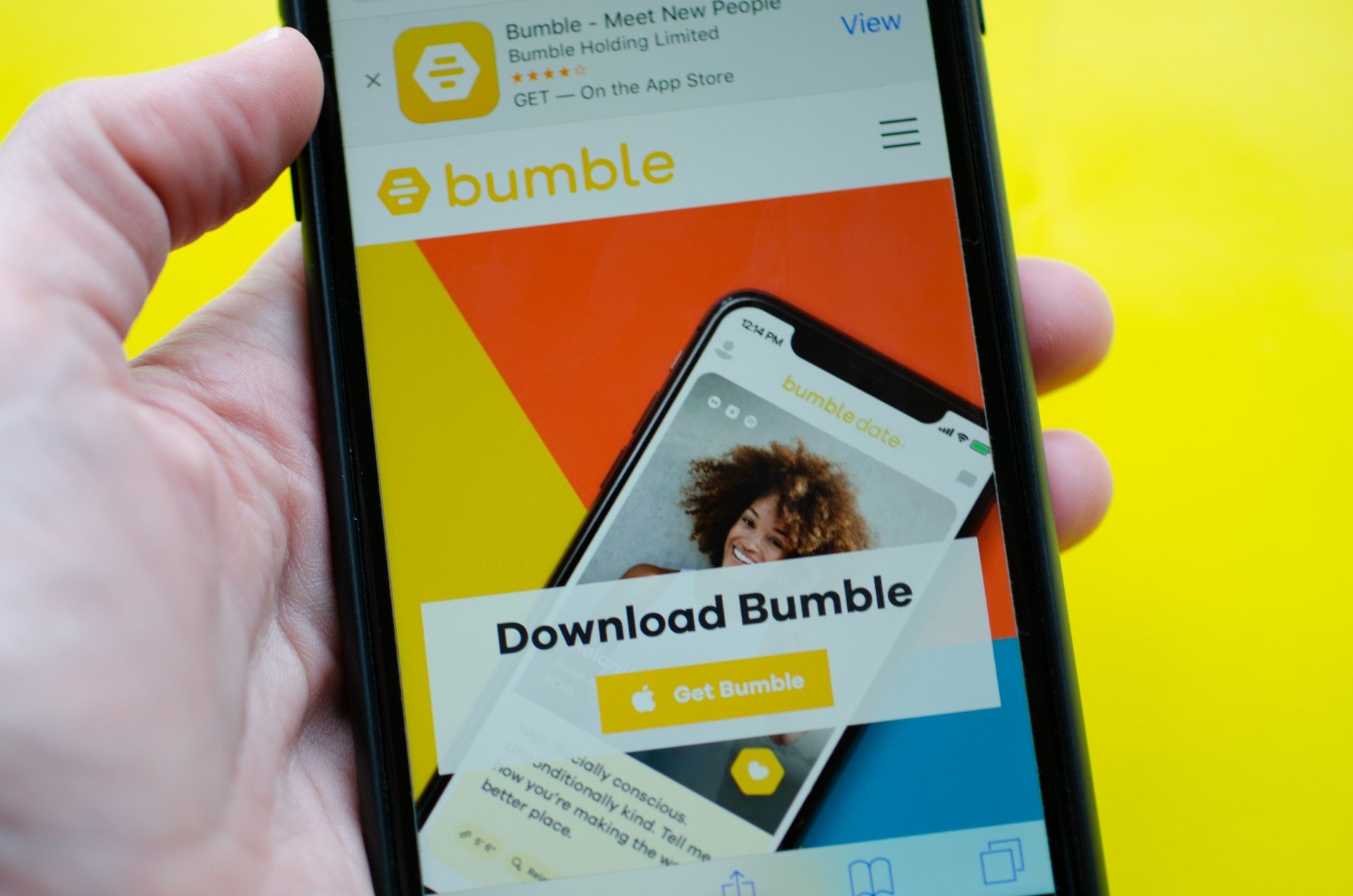 Person holds phone showing Bumble app download screen