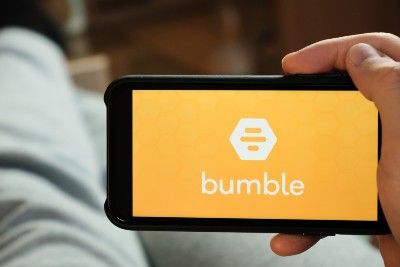 Man holds smartphone displaying Bumble app