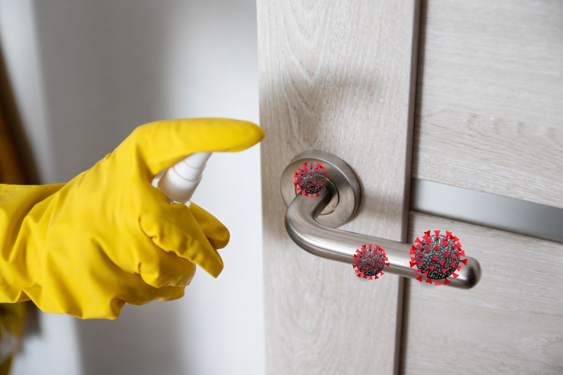 Hand in yellow glove sprays disinfectant on COVID-19-infected door handle