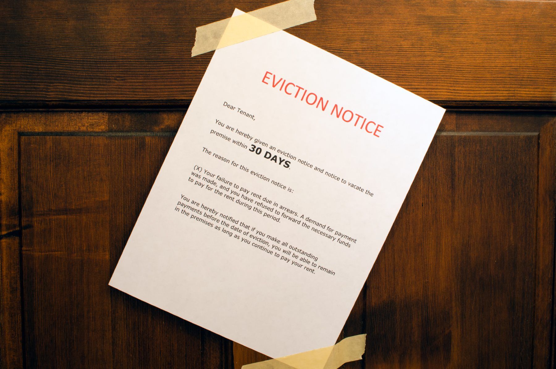 Eviction notice taped at an angle with masking tape on wood door - moratoriums ending