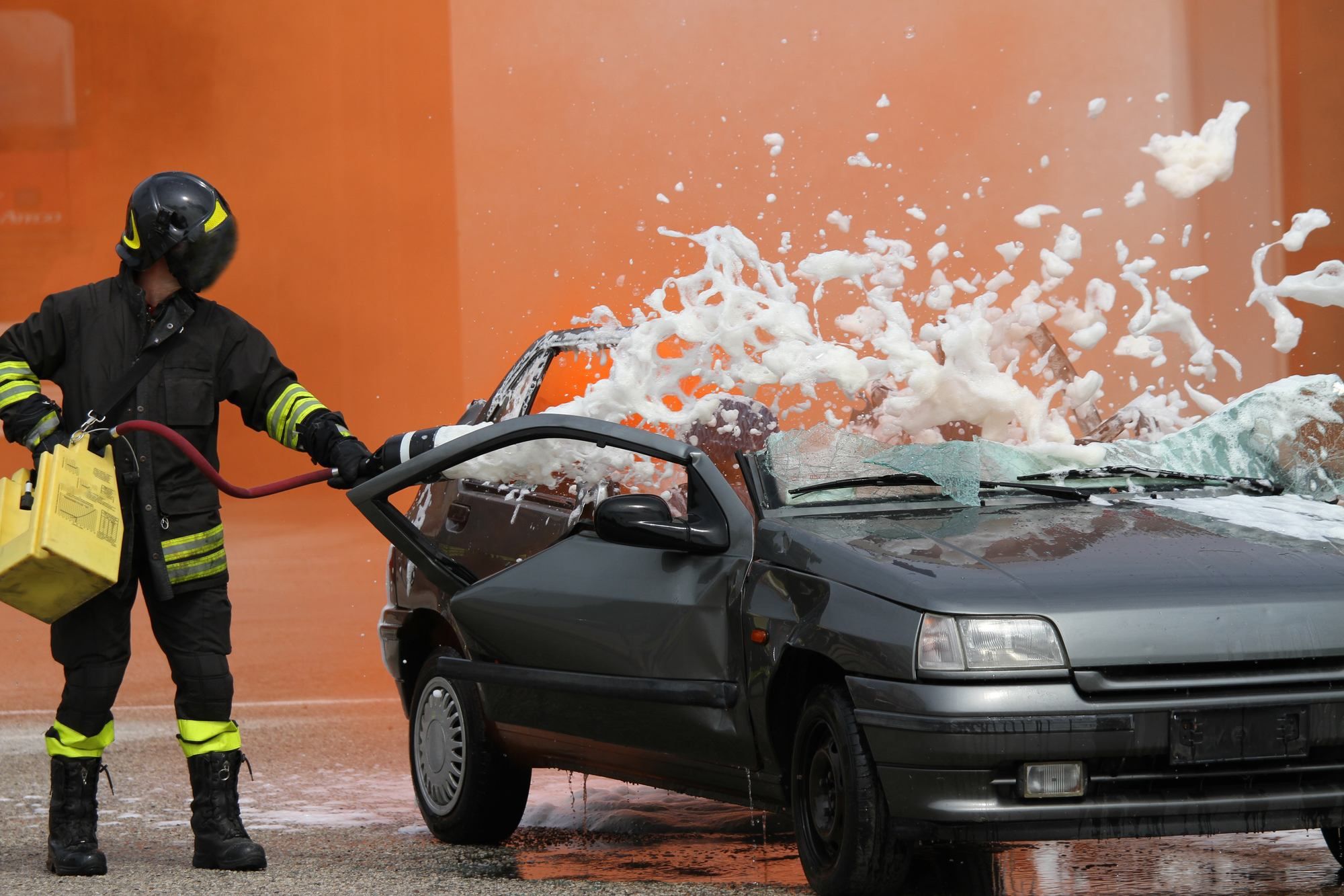 fireman putting out car fire with AFFF Foam