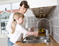 mom and daughter at sink getting glass of water