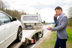 tow truck loading car with man on phone