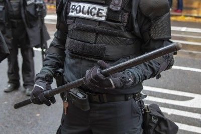 Officer in riot gear carries baton - portland protests