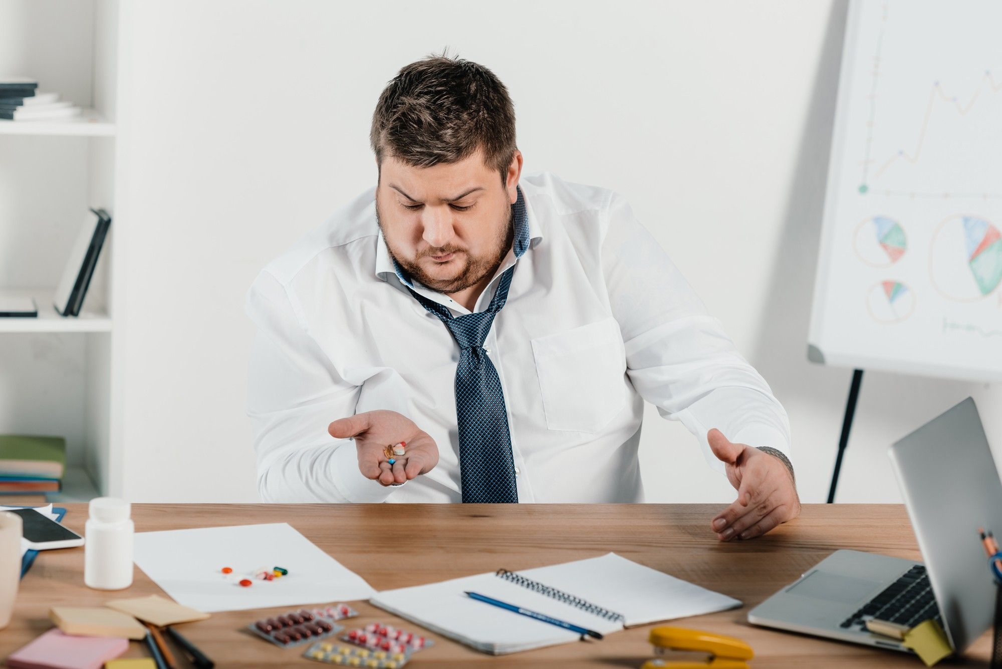 overweight man at work with weight loss pills