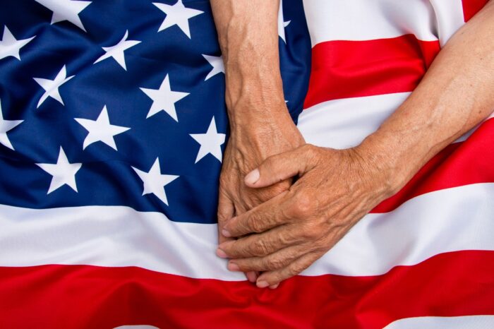 The older man put his hands on the us flag. The concept of caring for pensioners.