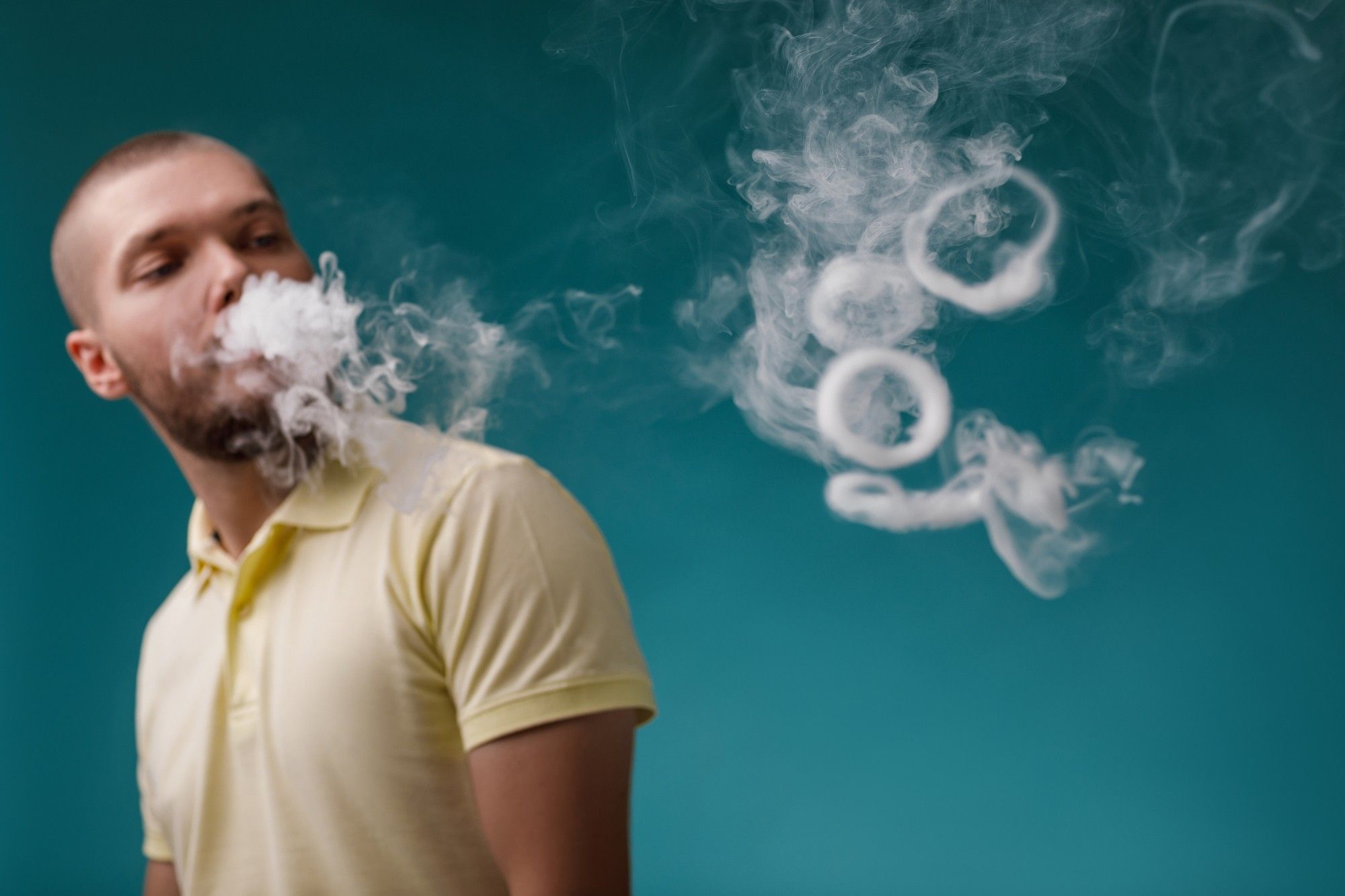 man smoking e-cigarette and blowing smoke rings