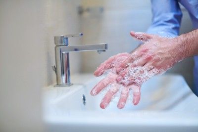 Man in blue shirt washing hands in bathroom sink