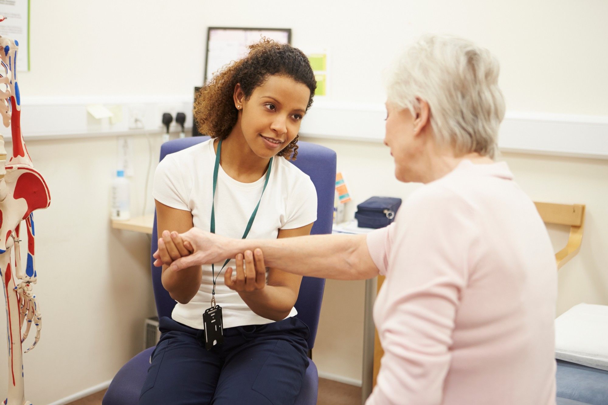 Female nurse examines elderly woman's arm