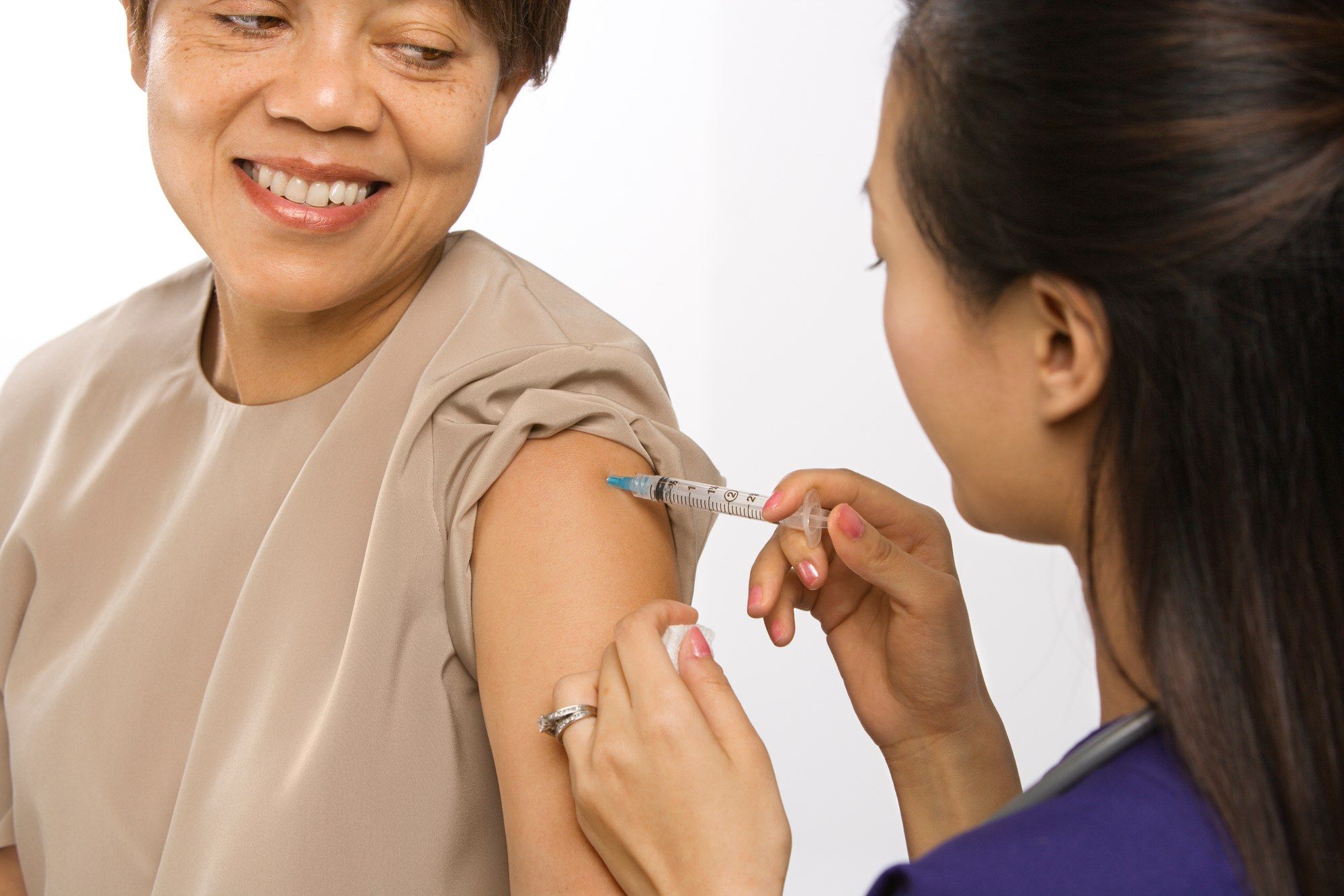 Female nurse vaccinates arm of female patient