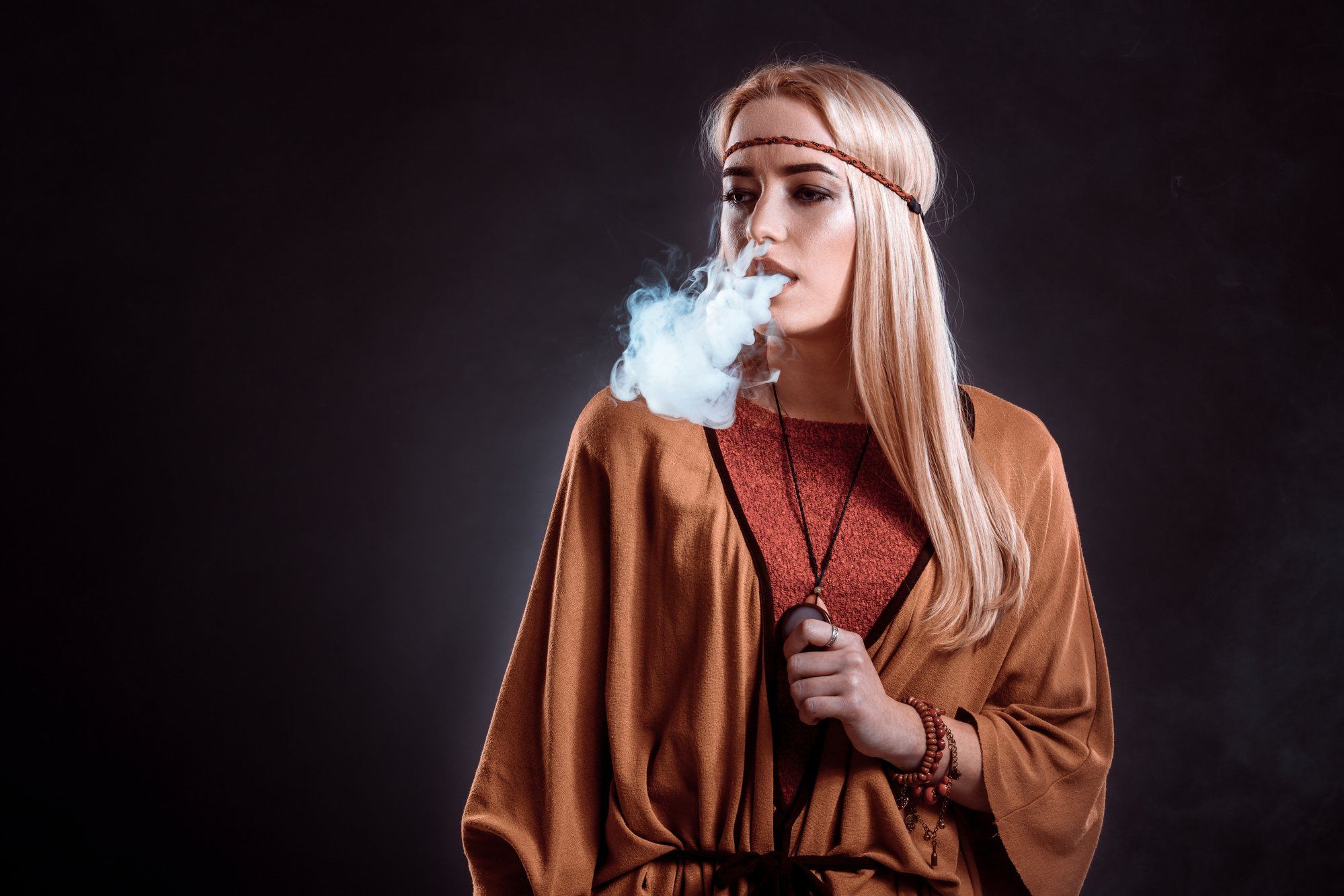 Young woman in Boho clothing vapes