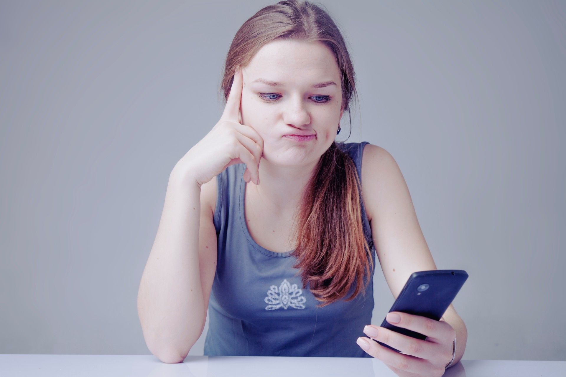 Annoyed girl looks at smartphone in her hand - nasty gal promo code