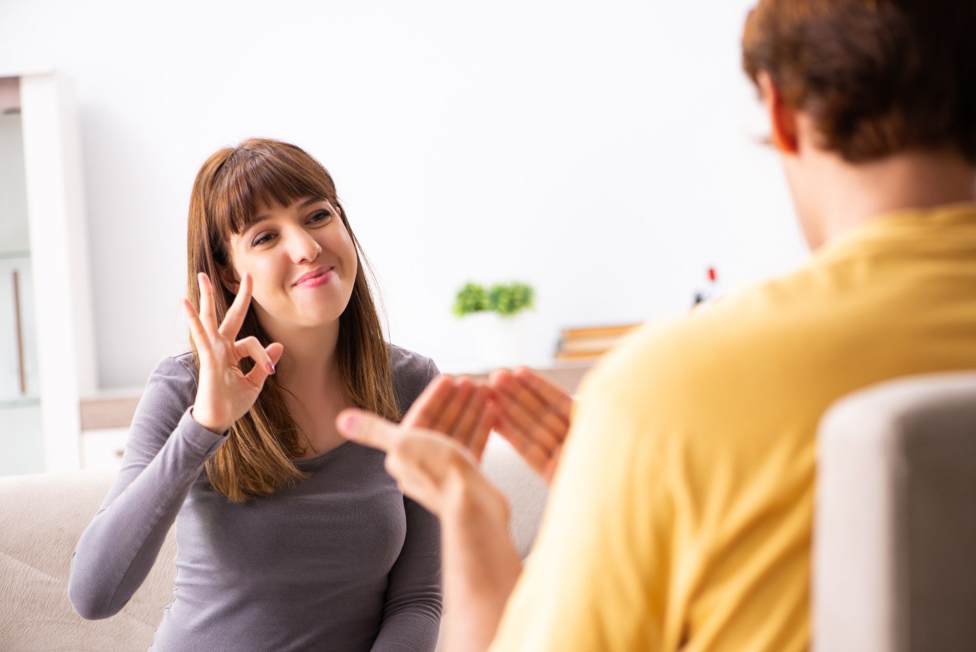 Smiling woman studies American Sign Language with a partner - ASL interpreter