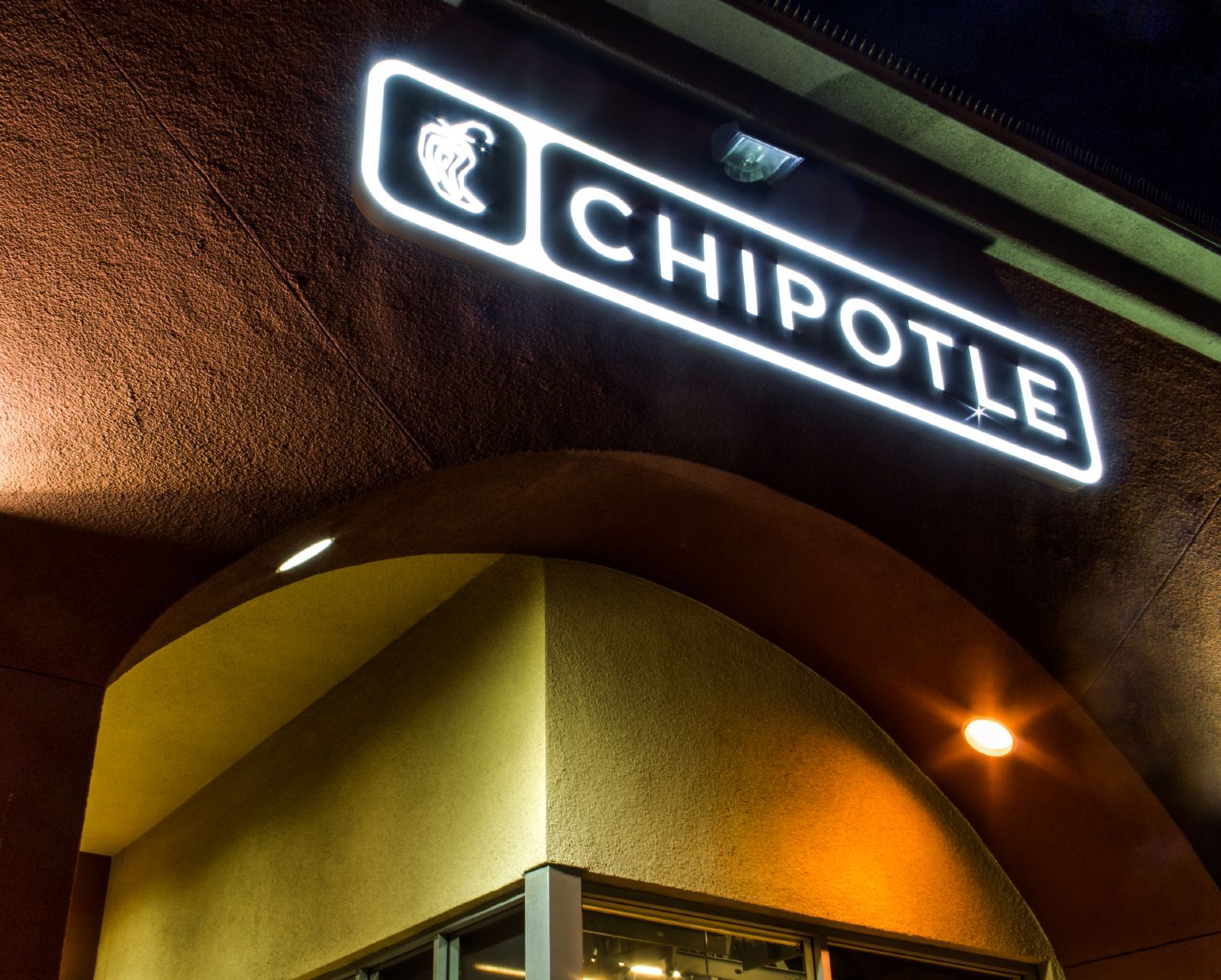 Chipotle sign on building at night - Chipotle employees