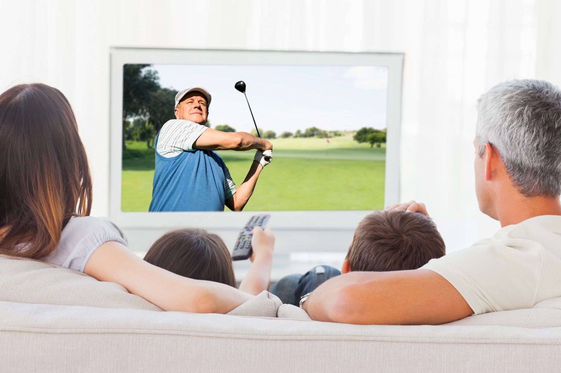 Rear shot of man and woman watching golf on TV with two children - NBCUniversal