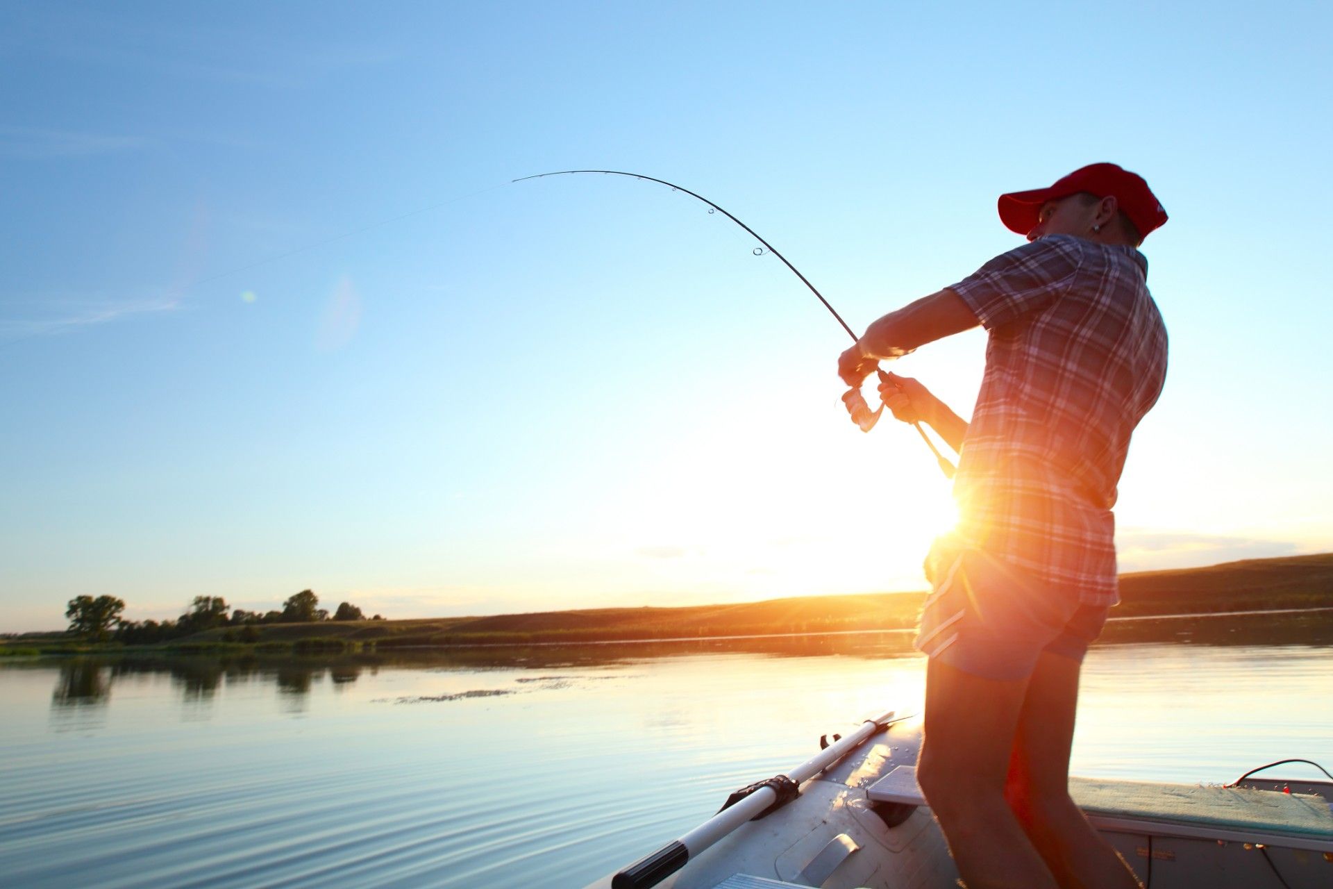 A person fishes with the sun on the horizon - Pure Fishing