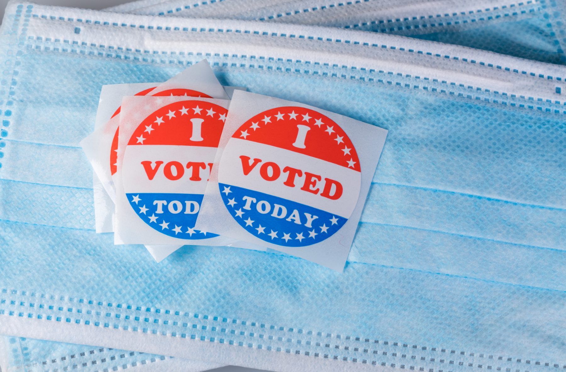 Circular "I voted today" stickers lie on top of light blue surgical masks - 