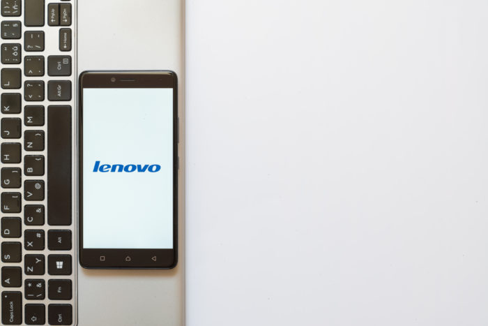 Lenovo logo on a smartphone with a Lenovo laptop