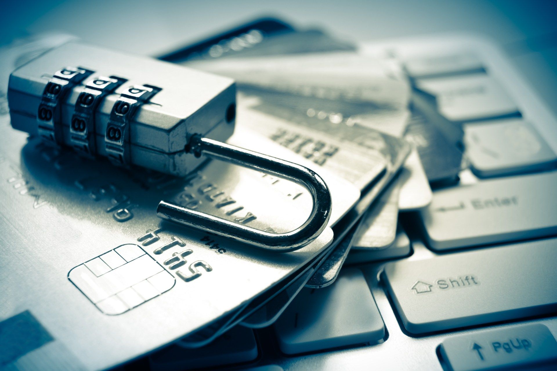An open combination lock lies on top of a stack of credit cards on top of a computer keyboard - Dave banking app