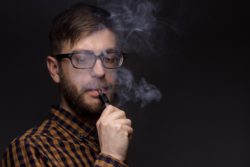 Man in glasses and beard vapes