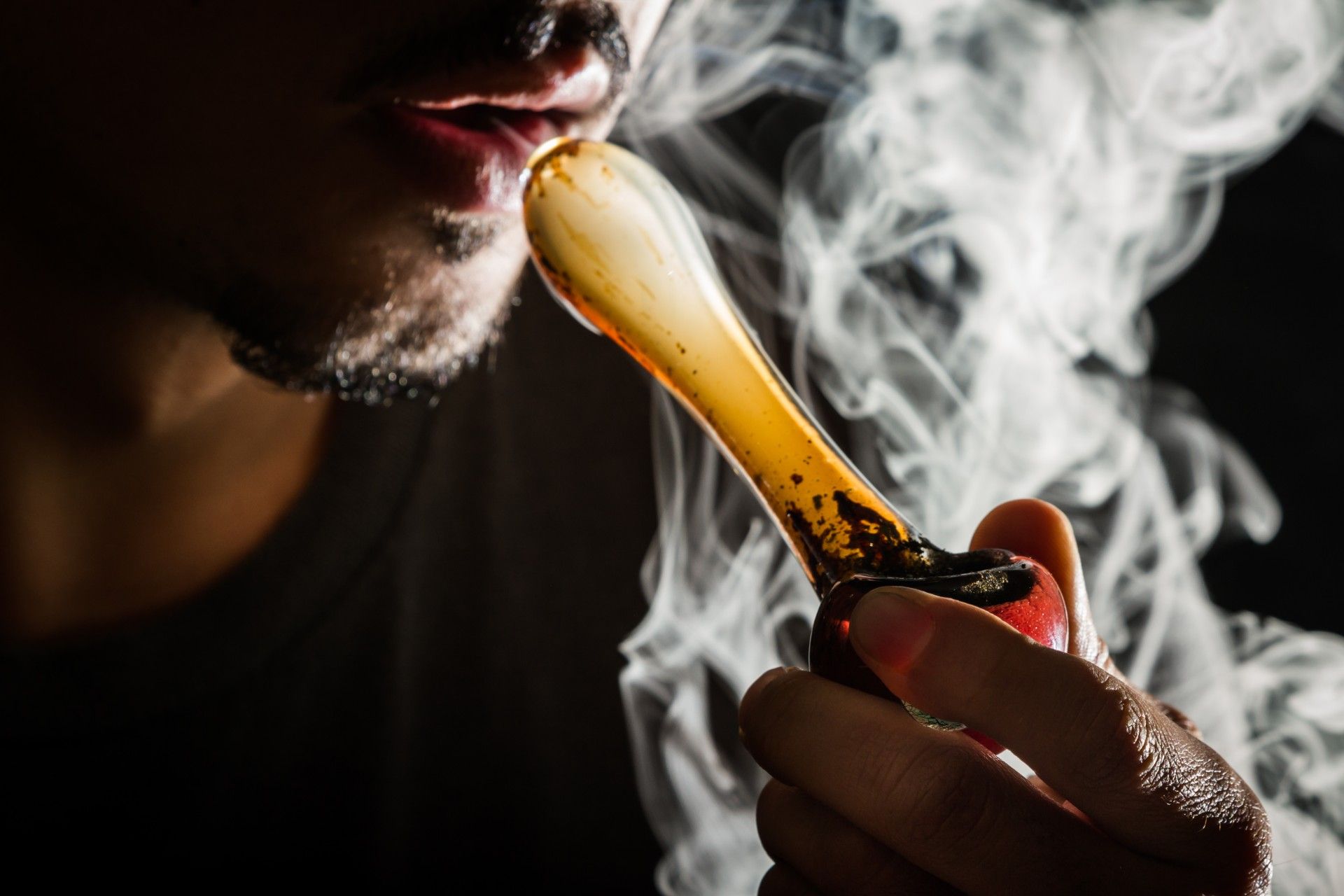A man uses a glass pipe to smoke marijuana - legalization of marijuana