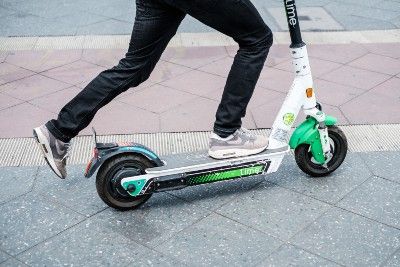 Close up of person's legs riding a Lime electric scooter - Lime scooter rental