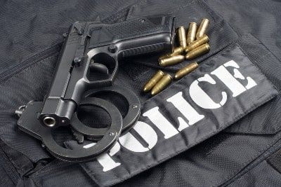 Gun, handcuffs and bullets lie on top of black police clothing - police brutality