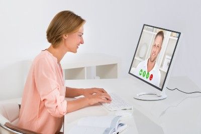 Woman holds a video chat with a man while sitting at a desk - Zoom privacy lawsuit