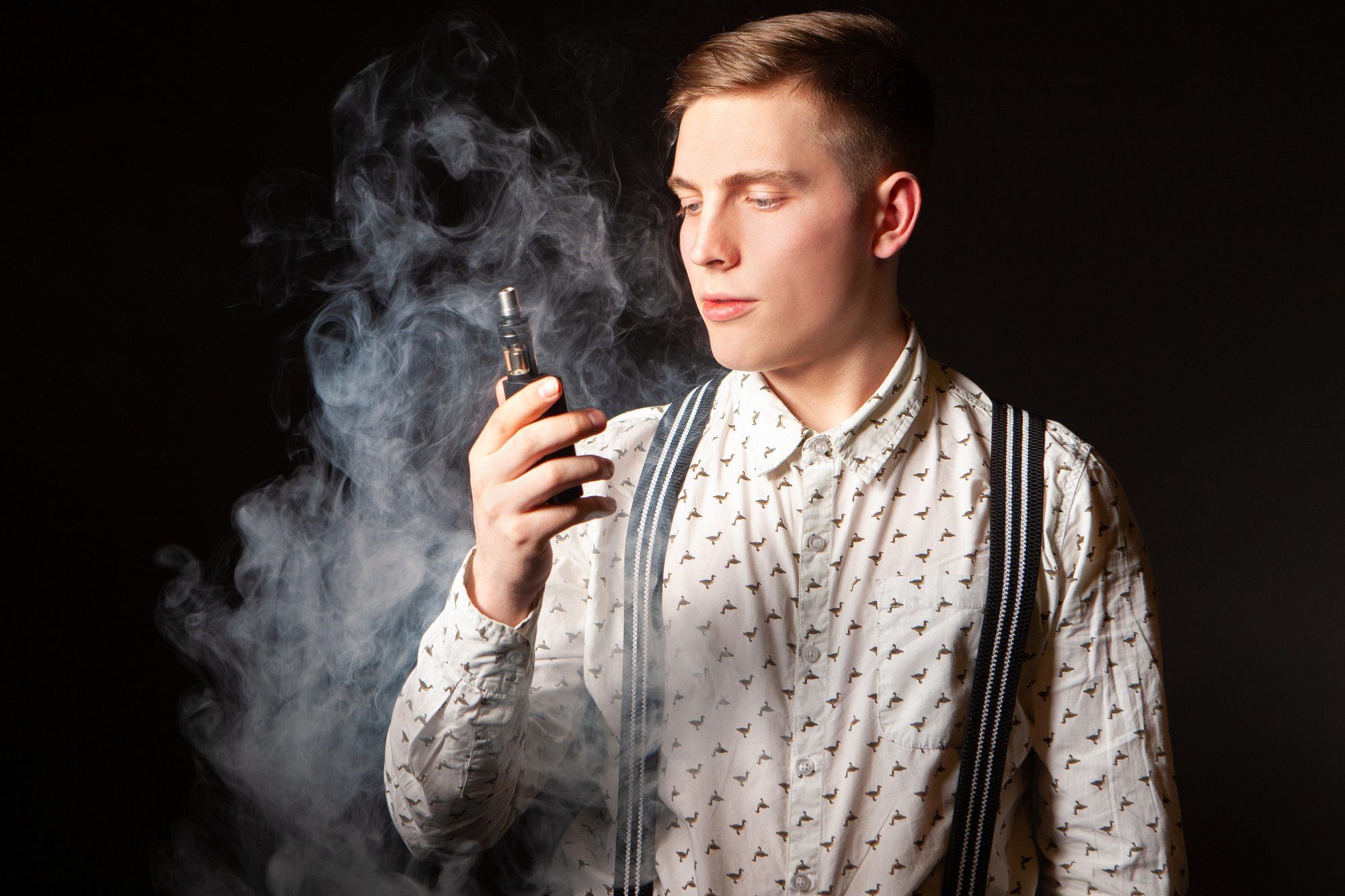 young well-dressed man vaping