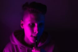 young teen male vaping under blacklight