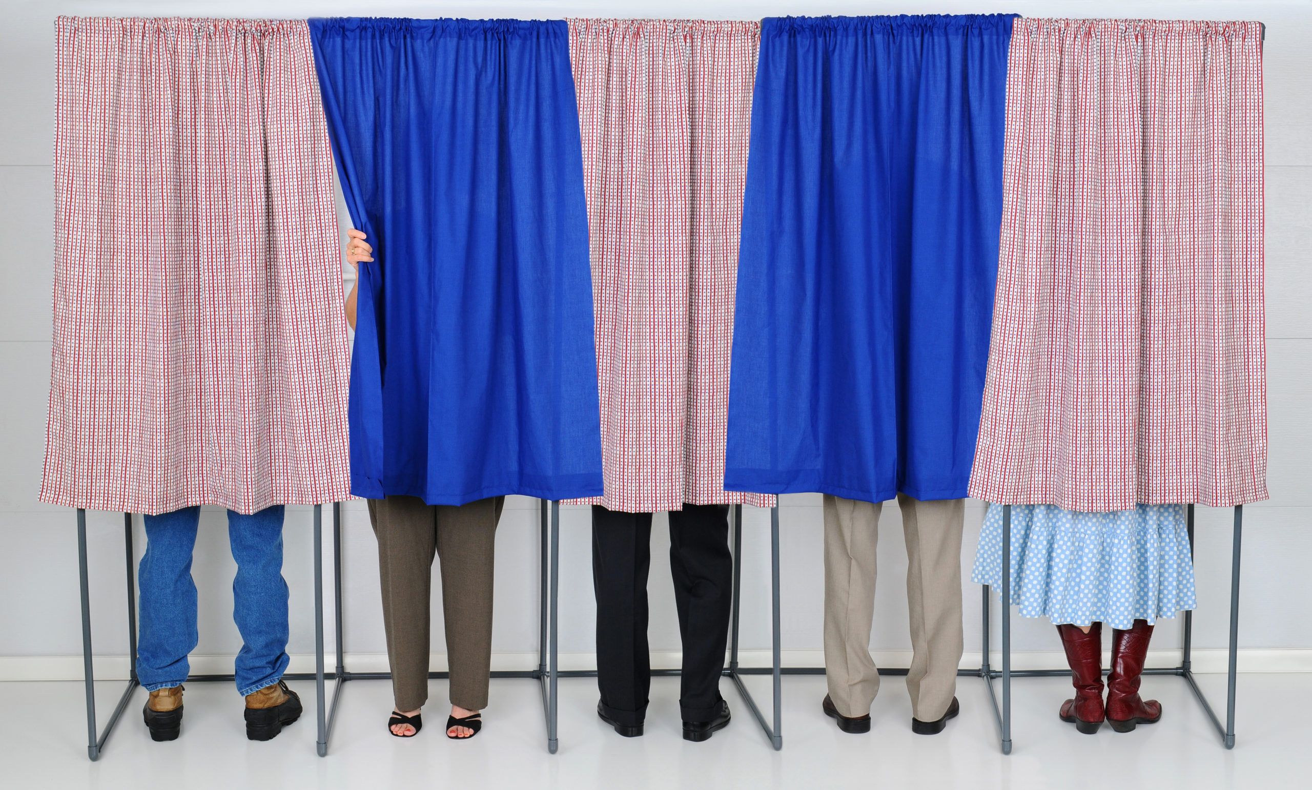 Voters stand in voting booths, concealed by red and blue curtains - photo id