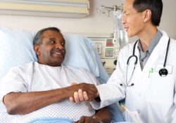 Male doctor shakes hand of male patient in hospital