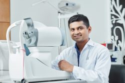 Male eye doctor sits in front of exam equipment