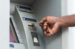 Male hand placing debit card in ATM terminal