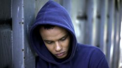 Young man in purple hoodie looks depressed