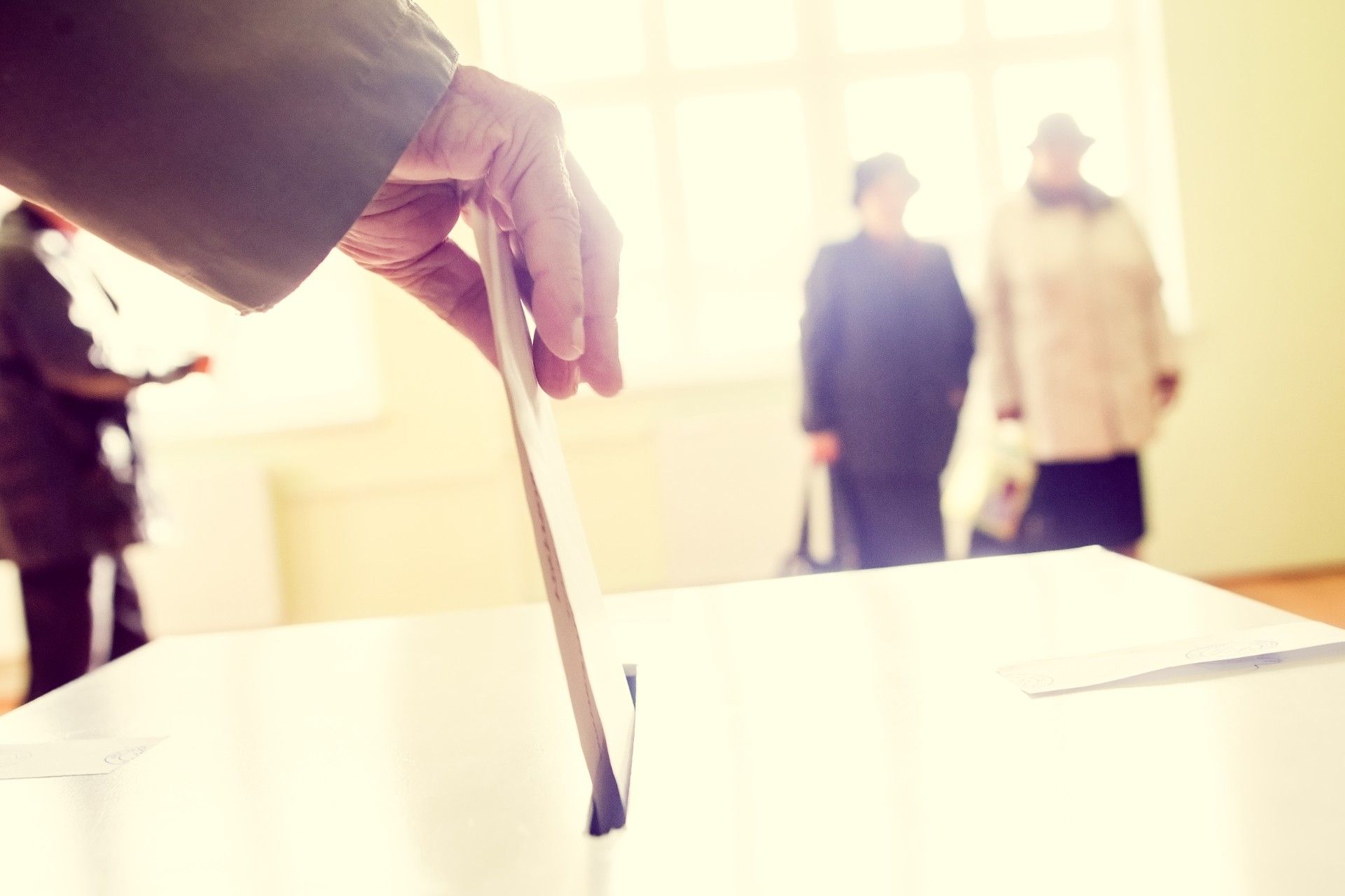 Man's hand puts ballot into ballot box - voting rights