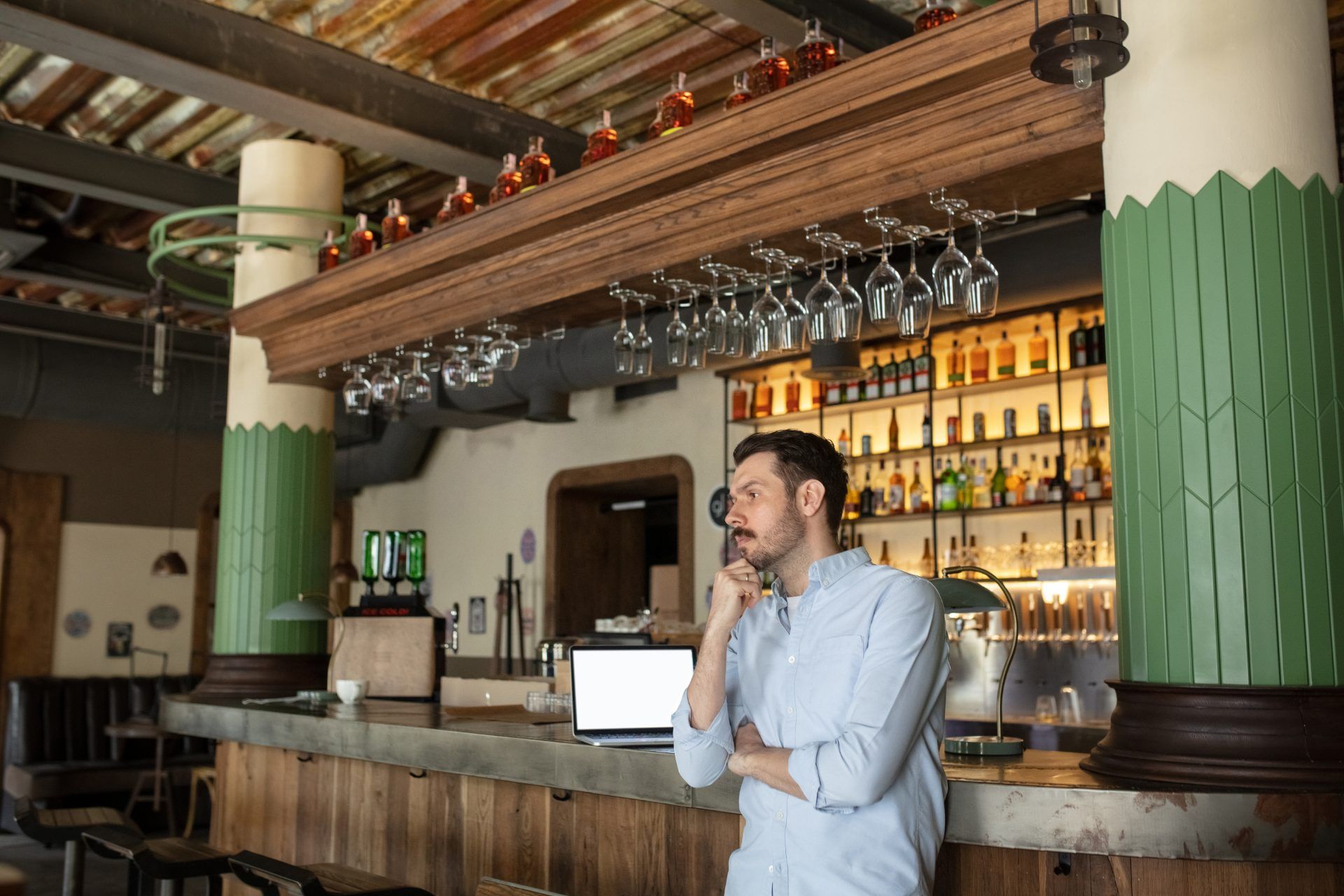 Man stands in closed bar with laptop on the bar - pandemic rules