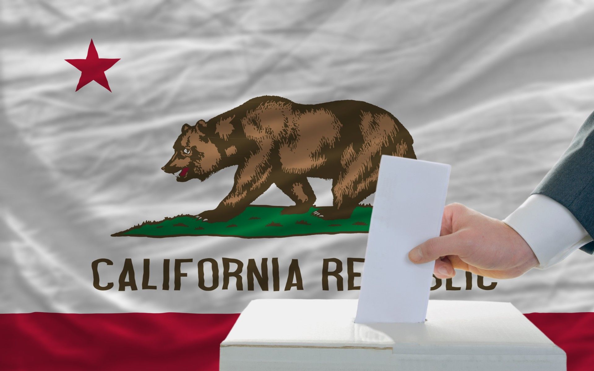 A man's hand puts a paper in a ballot box in front of a California flag - ballot initiatives