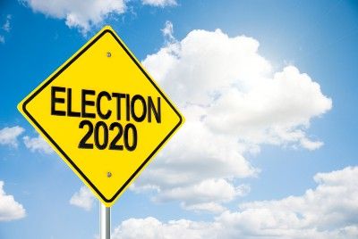 Yellow "election 2020" road sign against partly cloudy sky - early voting